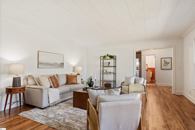 living area with baseboards, wood finished floors, and crown molding