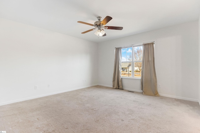 carpeted spare room featuring visible vents, ceiling fan, and baseboards