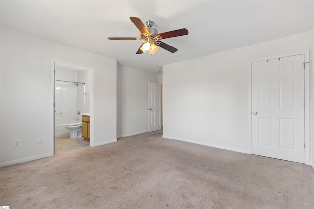 unfurnished bedroom featuring light carpet, connected bathroom, baseboards, and ceiling fan