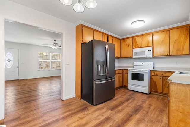 kitchen featuring light countertops, white appliances, brown cabinetry, and wood finished floors