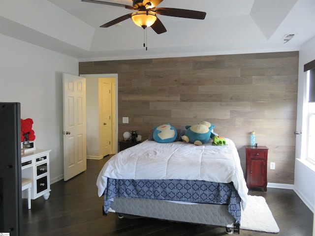 bedroom with ceiling fan, a raised ceiling, dark wood finished floors, and baseboards