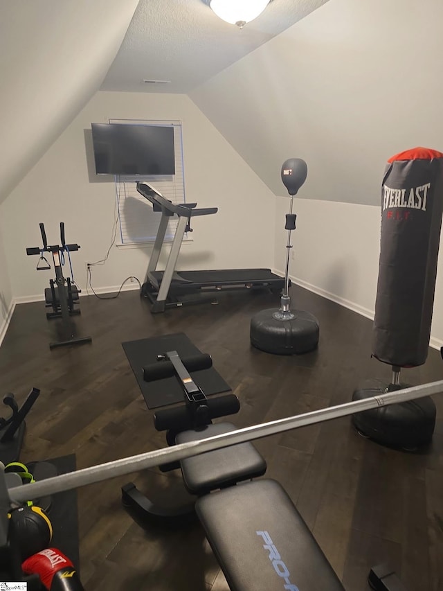 workout room featuring vaulted ceiling, wood finished floors, and baseboards