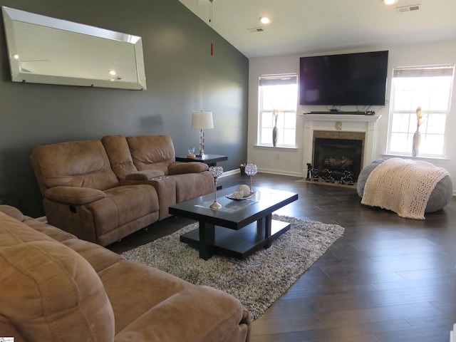 living area with dark wood-style flooring, lofted ceiling, visible vents, a premium fireplace, and baseboards