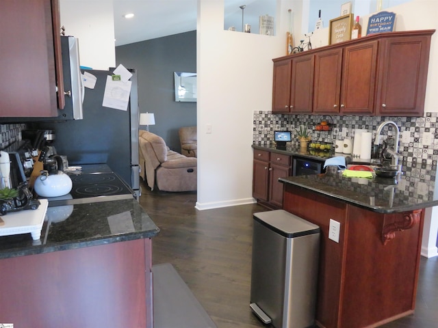 kitchen featuring a peninsula, dark wood-style floors, stove, and backsplash