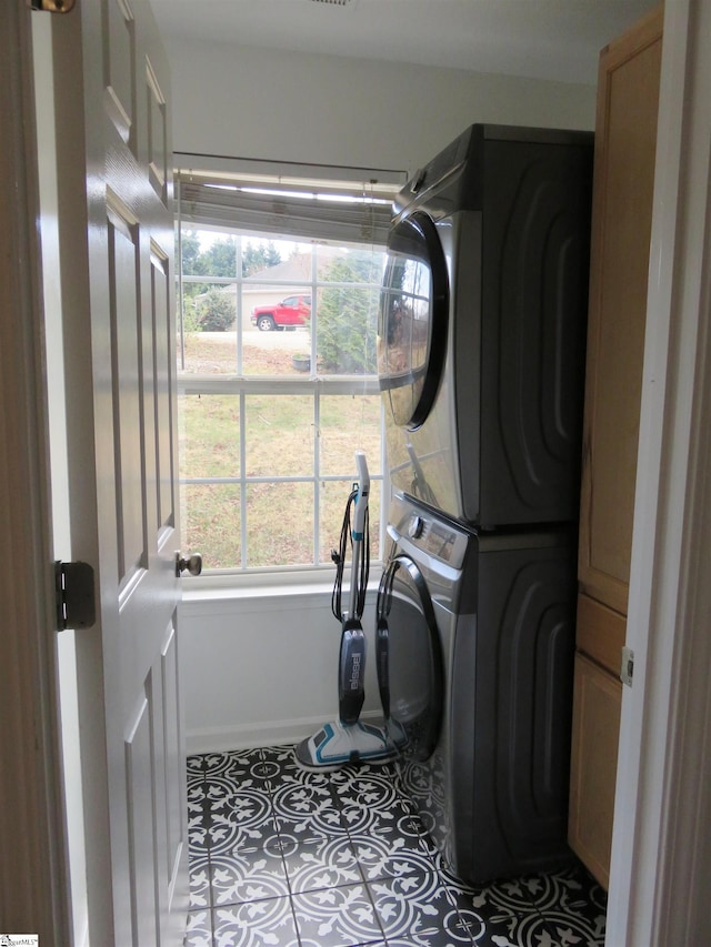 laundry area featuring tile patterned floors and stacked washer / drying machine