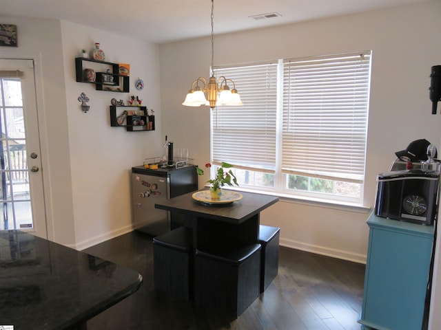 dining space with visible vents, dark wood finished floors, baseboards, and an inviting chandelier