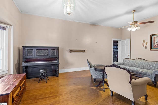 interior space with ornamental molding, ceiling fan, baseboards, and wood finished floors