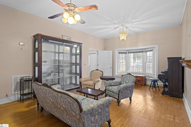 living area with ornamental molding, wood finished floors, and visible vents