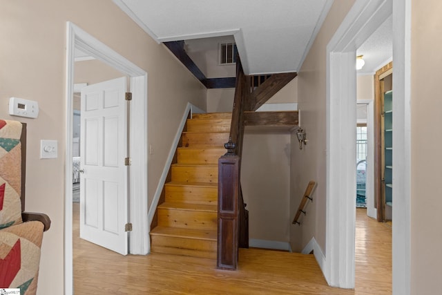 staircase with visible vents and wood finished floors