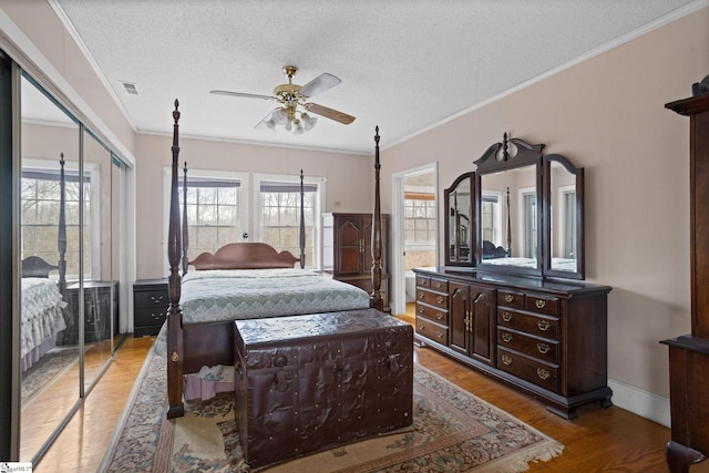 bedroom with ceiling fan, ornamental molding, a textured ceiling, light wood-style floors, and a closet