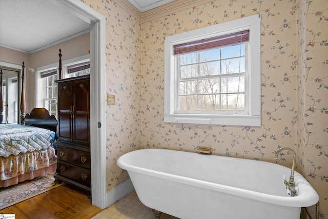 ensuite bathroom featuring wallpapered walls, connected bathroom, baseboards, and a freestanding bath