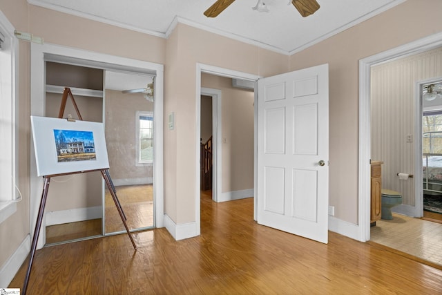 unfurnished bedroom with a ceiling fan, crown molding, baseboards, and wood finished floors