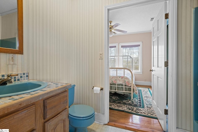 half bathroom featuring baseboards, visible vents, toilet, ceiling fan, and vanity