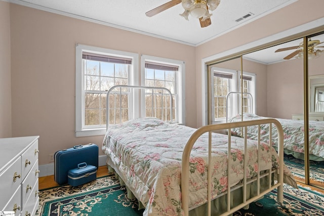 bedroom with visible vents, ceiling fan, a textured ceiling, crown molding, and a closet