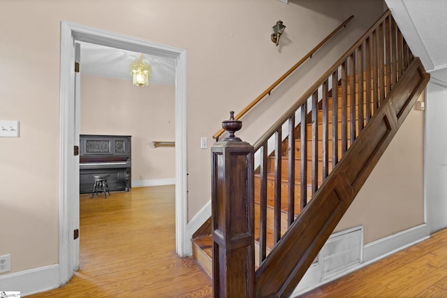 staircase with visible vents, baseboards, and wood finished floors