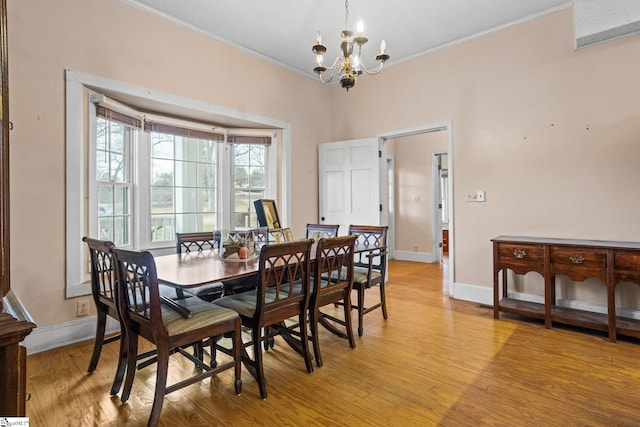 dining area featuring baseboards, crown molding, light wood finished floors, and an inviting chandelier