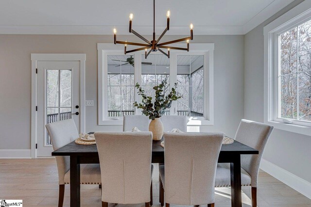 dining area featuring an inviting chandelier, a healthy amount of sunlight, baseboards, and wood finished floors