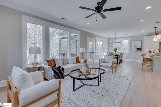 living room with baseboards, visible vents, ornamental molding, light wood-style floors, and recessed lighting