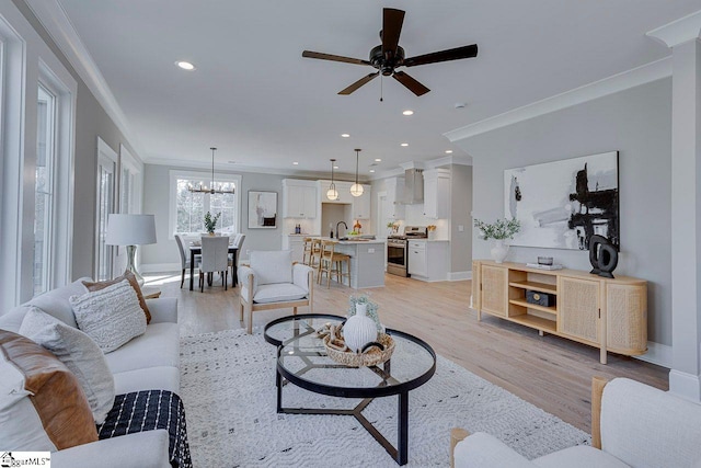 living room featuring light wood-style floors, baseboards, crown molding, and recessed lighting