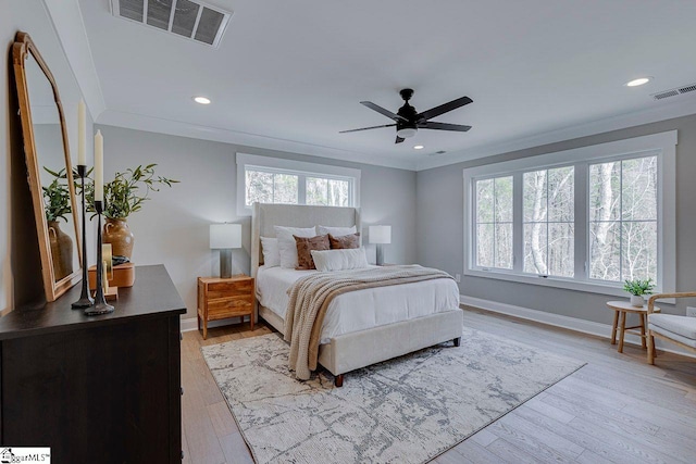 bedroom featuring light wood finished floors, ornamental molding, and visible vents