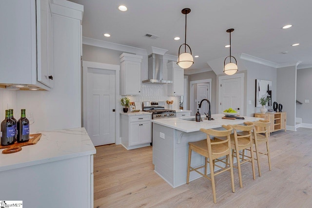 kitchen with visible vents, ornamental molding, gas stove, a sink, and wall chimney exhaust hood