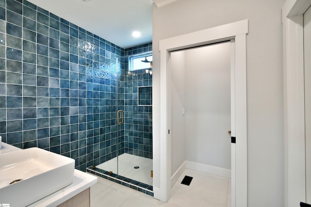 full bathroom featuring a stall shower, a sink, baseboards, and tile patterned floors