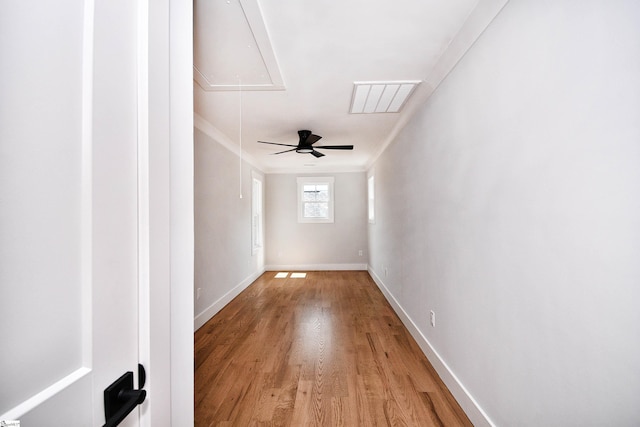 spare room featuring visible vents, light wood-style flooring, attic access, ornamental molding, and baseboards