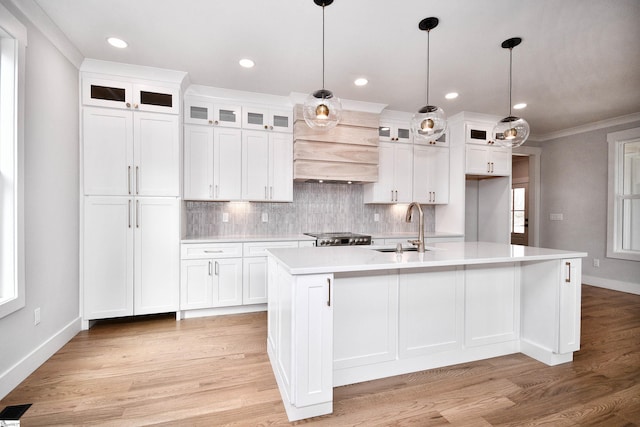 kitchen with light wood-type flooring, light countertops, crown molding, and backsplash