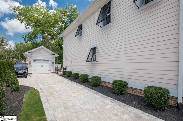 view of side of home featuring an outbuilding and decorative driveway