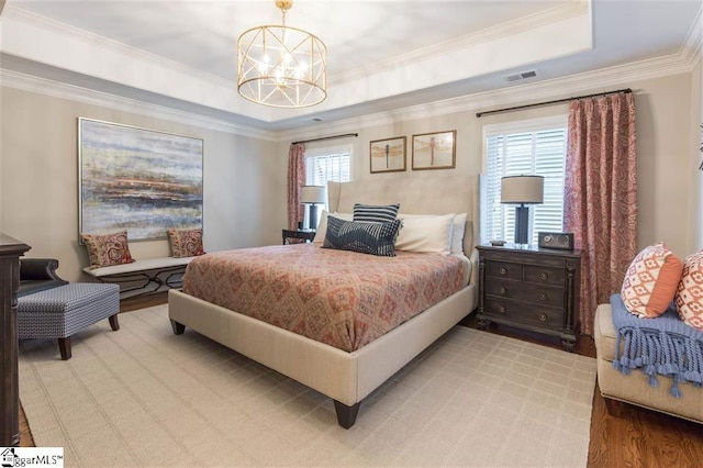 bedroom featuring light wood finished floors, visible vents, a raised ceiling, ornamental molding, and a notable chandelier