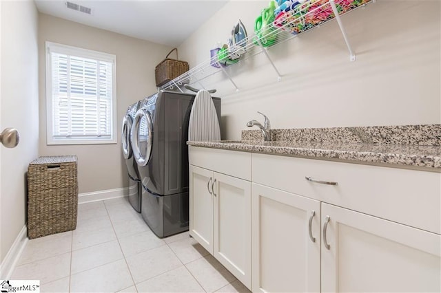 washroom featuring cabinet space, baseboards, visible vents, washing machine and clothes dryer, and light tile patterned flooring