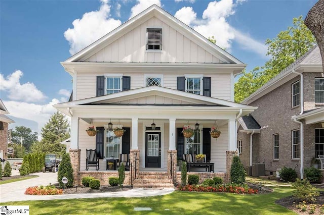 view of front of house featuring board and batten siding, a front yard, central AC, and a porch