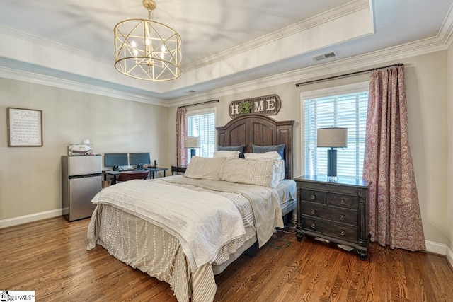 bedroom featuring visible vents, wood finished floors, freestanding refrigerator, a tray ceiling, and a chandelier