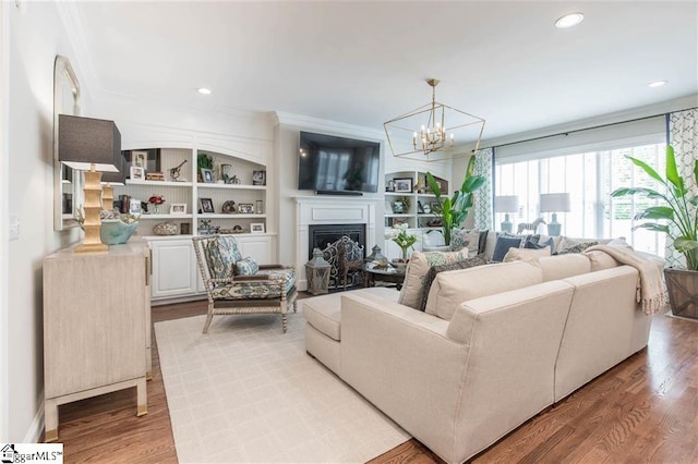 living room featuring light wood finished floors, a fireplace, crown molding, and recessed lighting