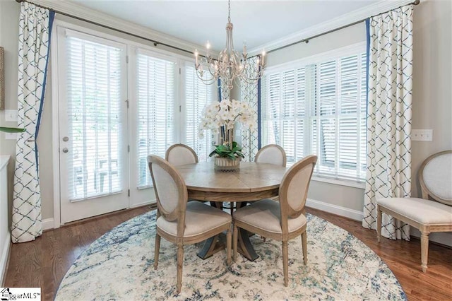 dining space featuring baseboards, ornamental molding, wood finished floors, and an inviting chandelier