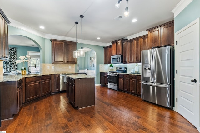 kitchen featuring appliances with stainless steel finishes, dark brown cabinetry, visible vents, and a center island