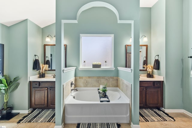 bathroom with two vanities, tile patterned flooring, a sink, and a bath