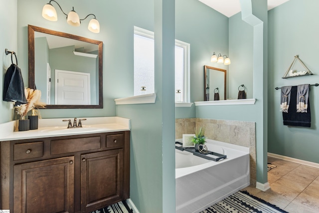 full bath featuring baseboards, a bath, and vanity