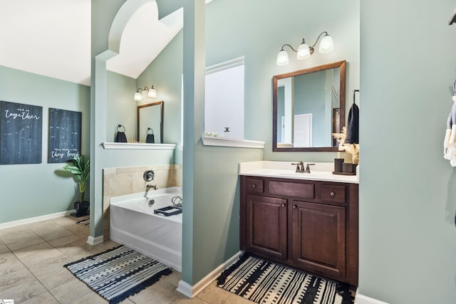 bathroom featuring a garden tub, baseboards, and vanity