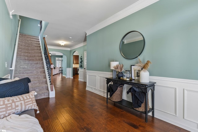 hall featuring stairway, wood-type flooring, arched walkways, and a wainscoted wall