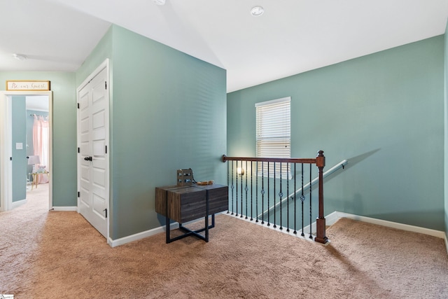 hallway featuring carpet, baseboards, and an upstairs landing