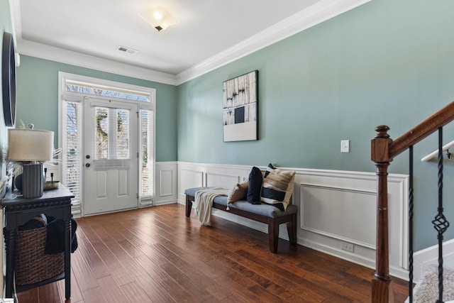 entryway with ornamental molding, wood finished floors, visible vents, and stairs