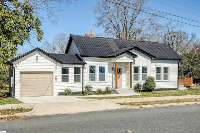 view of front of property with a garage, concrete driveway, metal roof, and a chimney