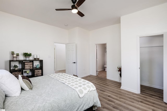 bedroom with connected bathroom, wood finished floors, baseboards, a spacious closet, and a closet