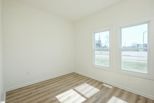 spare room featuring light wood finished floors, visible vents, baseboards, and a wealth of natural light