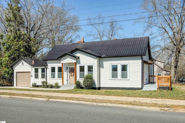 view of front of home with a garage, metal roof, and a chimney