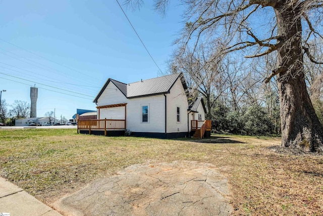 view of home's exterior with metal roof, a wooden deck, and a lawn