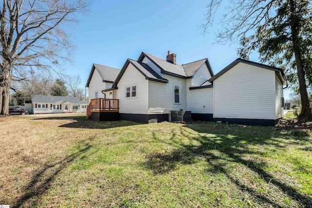 rear view of house with a deck, metal roof, a yard, and a chimney