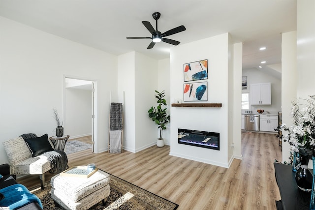 living room with recessed lighting, a ceiling fan, a glass covered fireplace, light wood-type flooring, and baseboards