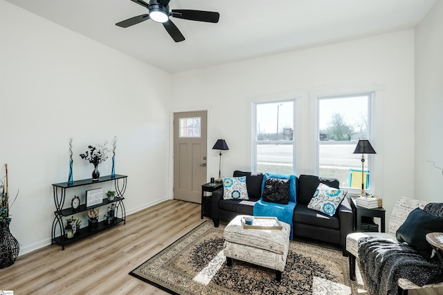 living room with light wood finished floors, ceiling fan, and baseboards